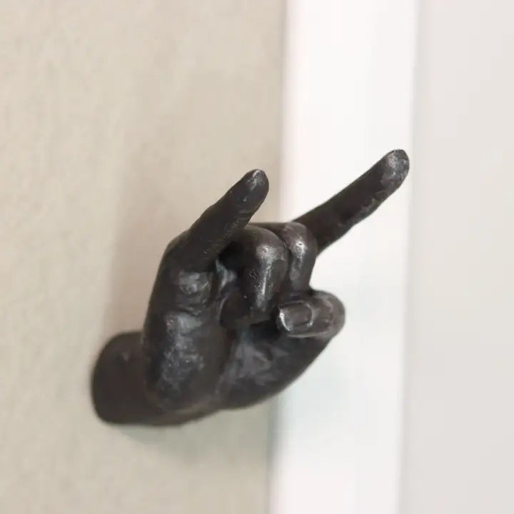 A wall-mounted coat hook shaped like a hand making a rock gesture sign.