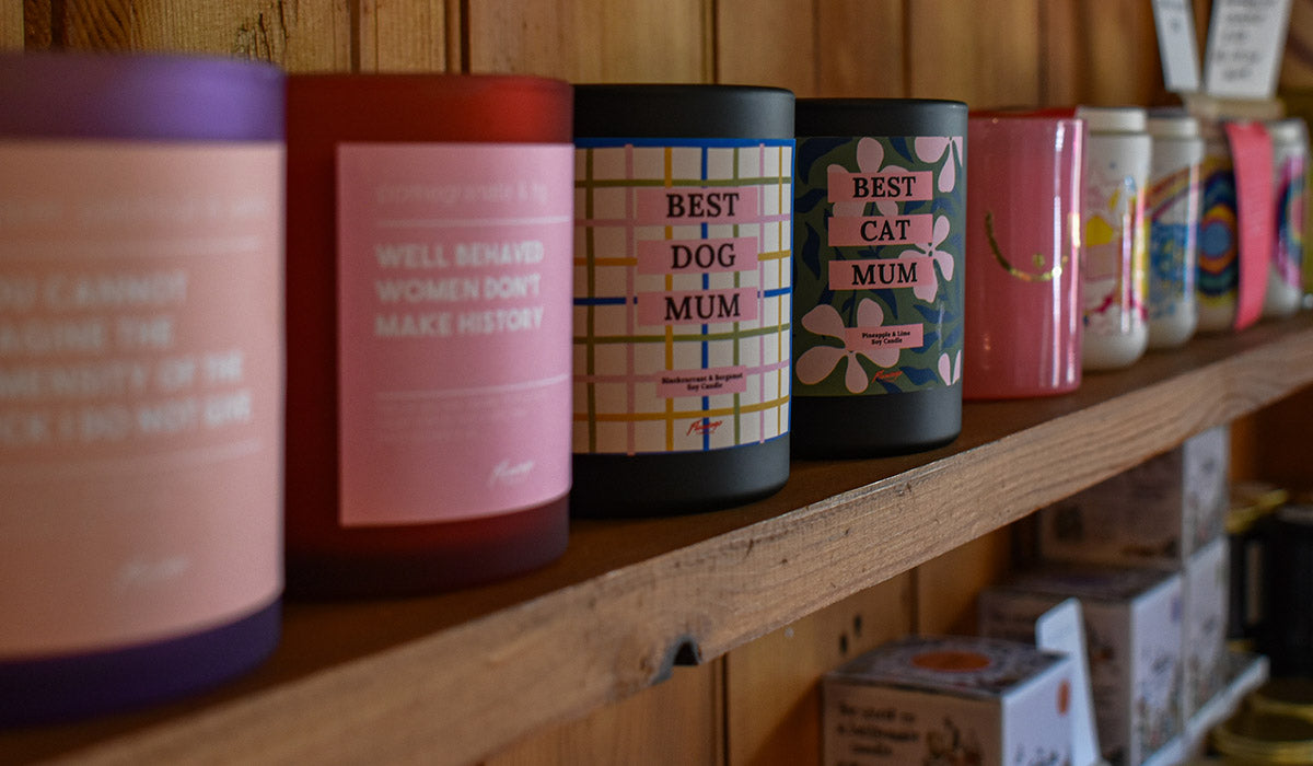 Row of colorful candles with text on a wooden shelf.