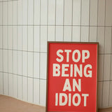Stop Being An Idiot | Cream and Red |   Poster Size  A3 Framed in white frame